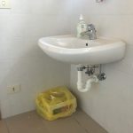 Lavandino a parete con tubature a vista in un bagno